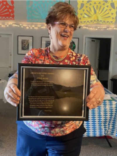 Committee member, displays an award for Steve Ricks at the Octoberfest Volunteer Forum.